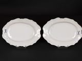 two white plates with blue trims on them sitting on a black surface