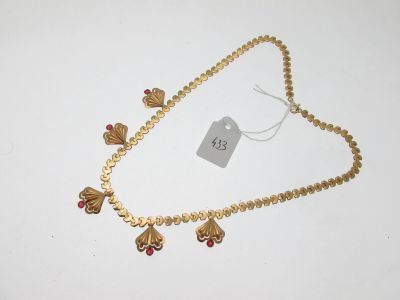 un gros plan d'un collier en or orné de perles rouges sur un fond blanc
