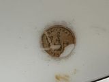 a white toilet with a gold lid and a coin on it