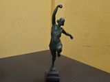 une statue représentant une femme tenant une raquette de tennis posée sur une table