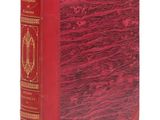 un vieux livre à la couverture rouge posé sur une surface blanche