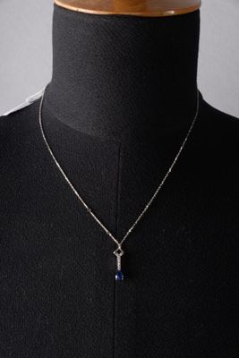 a black mannequin torso with a silver necklace and a blue stone pendant
