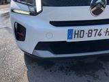 the front end of a white car with a number plate on it