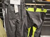 trois paires de pantalons de ski suspendues à un portant dans un magasin