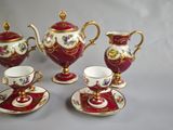 four pieces of red and gold tea set with matching cups and saucers