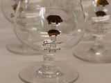 four wine glasses sitting on a table with gold trimmings