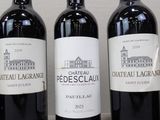 three bottles of red wine are lined up on a table
