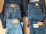 plusieurs paires de jeans pour homme posées sur une boîte en carton
