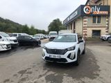 La voiture blanche est garée devant l'immeuble, sur le parking.