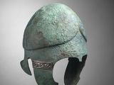 a close up of a bronze helmet on a gray background