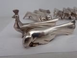 a silver figurine of a bird on a piece of paper