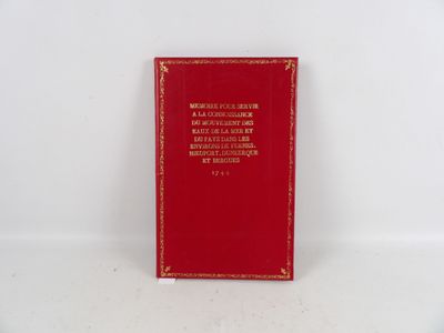 un livre rouge posé sur une table blanche à côté d'un mur blanc