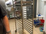 a man that is standing in a kitchen with a rack of food