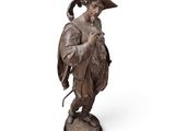 une statue en bronze représentant un homme avec un chapeau et une canne