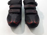 la paire de chaussures noires et rouges repose sur une surface blanche