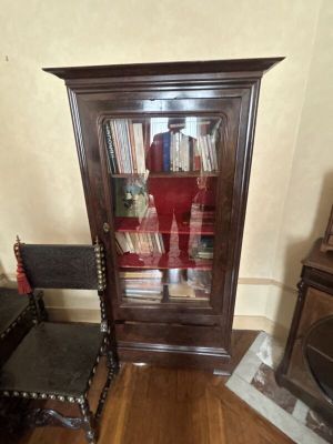 une armoire en bois avec une porte vitrée, devant laquelle se trouve une chaise