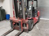 un chariot élévateur rouge dans un entrepôt avec un conteneur bleu