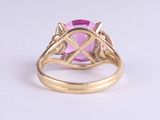 a close up of a pink stone ring on a white surface
