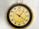 une horloge dorée et noire accrochée à un mur blanc