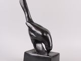 a black sculpture of a bird sitting on top of a wooden block