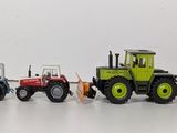 several toy tractors are lined up in a row on a white surface