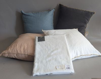 three pillows and a blanket on a bed with a tag on it