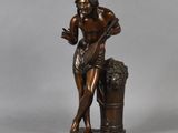 a bronze statue of a man holding a bucket of grapes