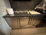 une cuisine équipée d'un évier et d'un plan de travail sur lequel est posé un rouleau de papier toilette