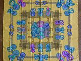 une écharpe jaune ornée de papillons bleus et roses, posée sur un parquet