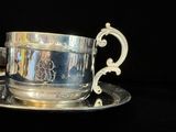 une tasse et une soucoupe en argent posées sur un plateau en argent