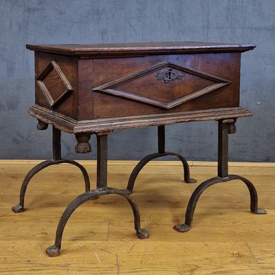 une petite boîte en bois posée sur un socle, sur un plancher en bois