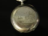 a silver pocket watch sitting on top of a black surface