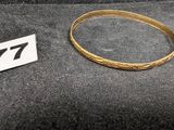 un gros plan d'un bracelet en or sur lequel figure le chiffre 77