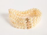 a close up of a bracelet with pearls on a white surface