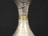 a silver and gold vase sitting on a black surface