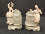 two figurines of a woman and a man with a birdcage