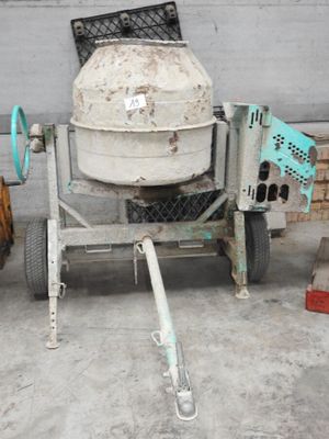 une bétonnière posée sur un chariot devant un immeuble