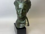 un buste en bronze représentant la tête d'une femme, posé sur un socle noir