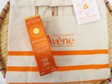 an orange and white bag sitting on top of a table next to a bottle of sunscreen