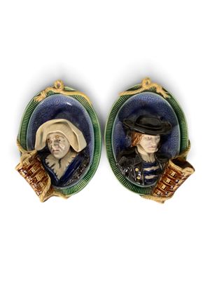 une paire de portraits en porcelaine représentant une femme et un homme coiffés d'un chapeau