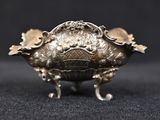 an antique silver plated bowl on a black surface