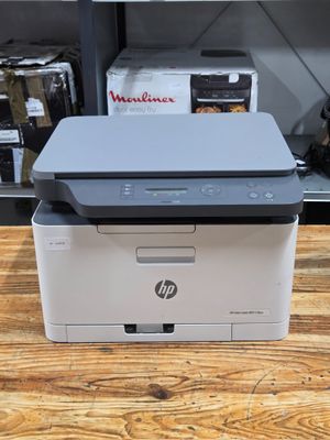 a printer sitting on top of a wooden table in front of a shelf