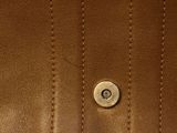 a close up of a brown leather jacket with a button