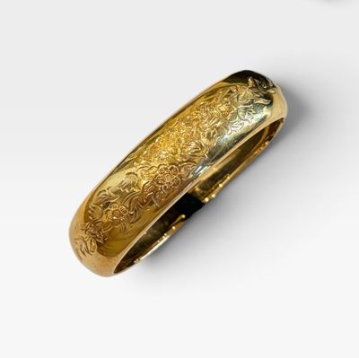 un gros plan d'un bracelet en or posé sur une surface blanche