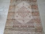 rug on the floor in the middle of a room with a chair in the background