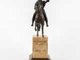 a bronze statue of a man riding a horse on a marble pedestal