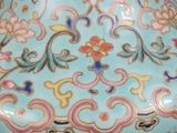 a hand holding a blue vase with a floral design on it