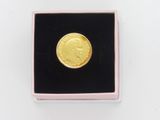 a close up of a gold coin in a pink box