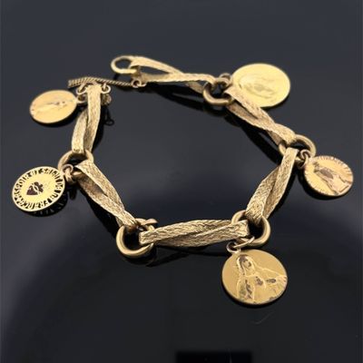 un gros plan d'un bracelet en or orné de pièces de monnaie, posé sur une surface noire