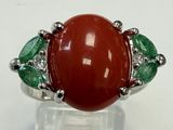 an image of a ring with a red stone surrounded by green stones